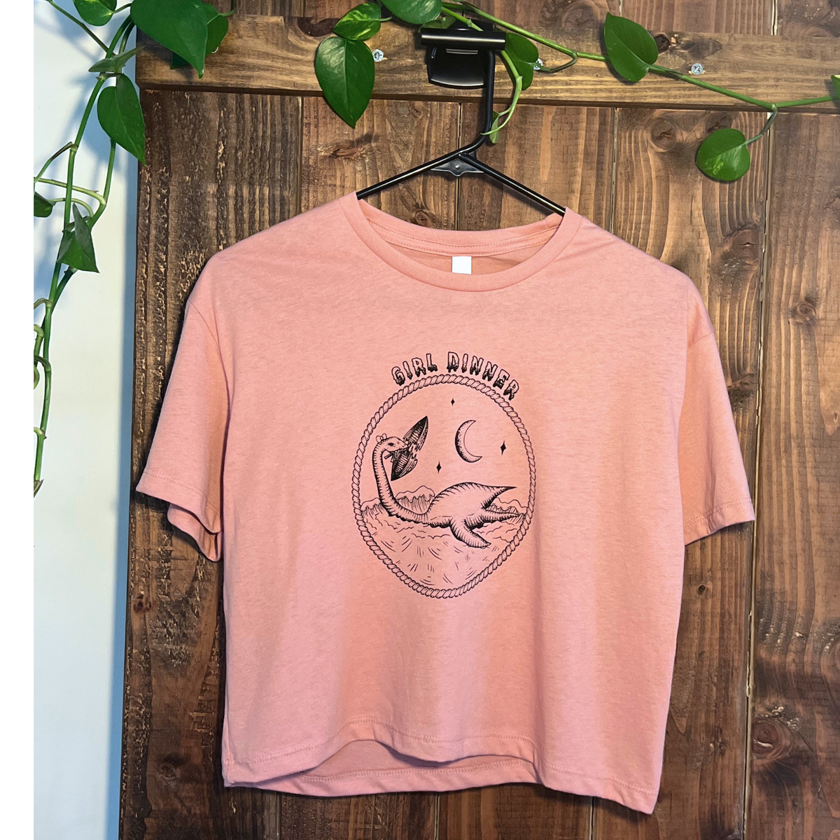 Plesia Girl Dinner crop top in desert pink from Cryptid Records, shown with a trucker hat