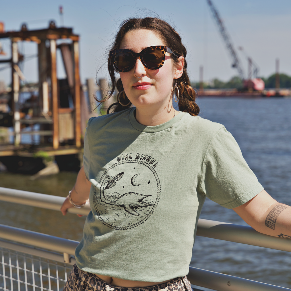 Model wearing Plesia Girl Dinner graphic t-shirt from Cryptid Records in sage green