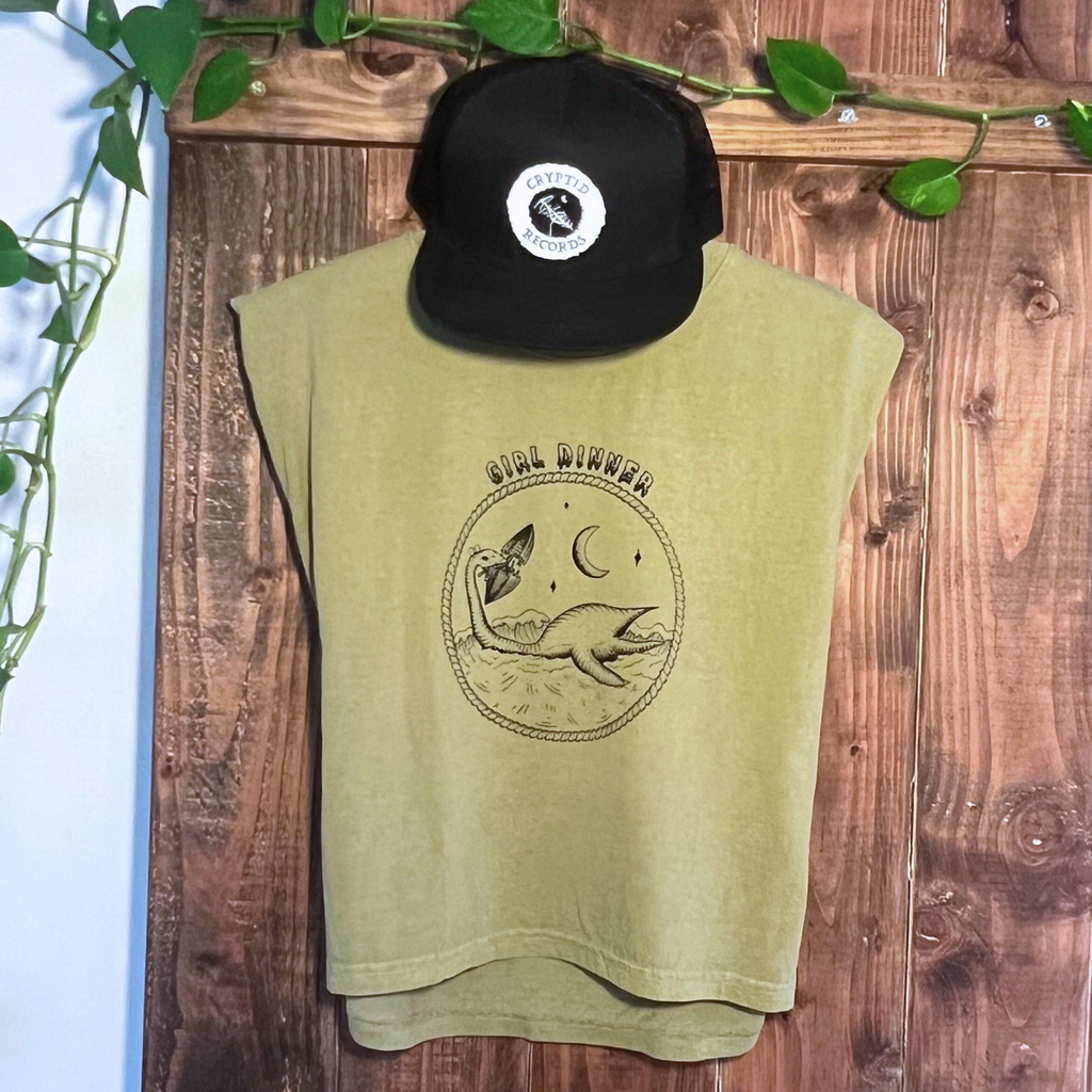 Plesia Girl Dinner muscle tank hanging with a Cryptid Records logo trucker hat