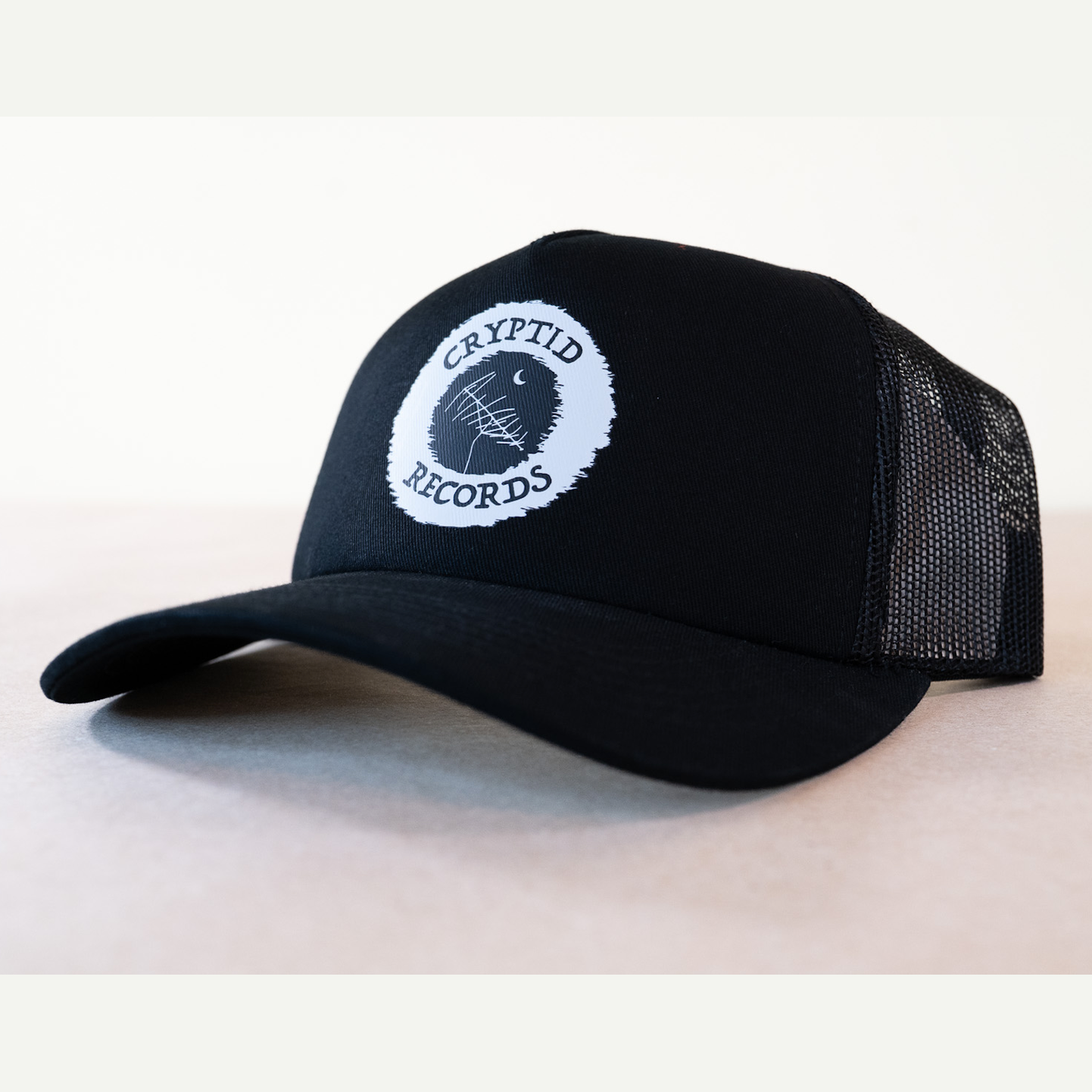 Cryptid Records logo black curved brim trucker hat, side view