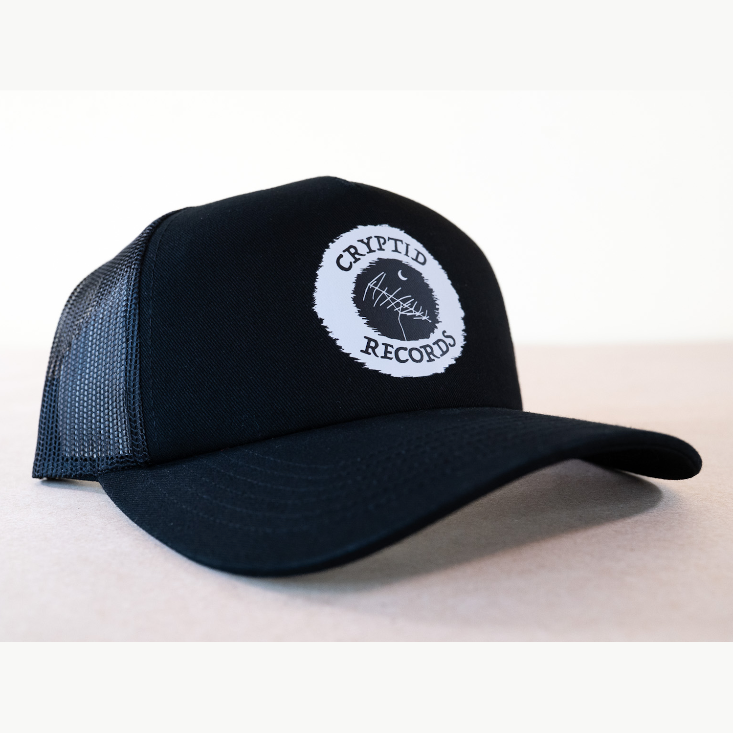 Cryptid Records logo black curved brim trucker hat, close up view